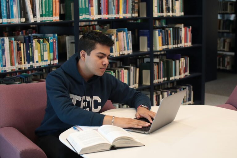 Student studying with laptop and books in library