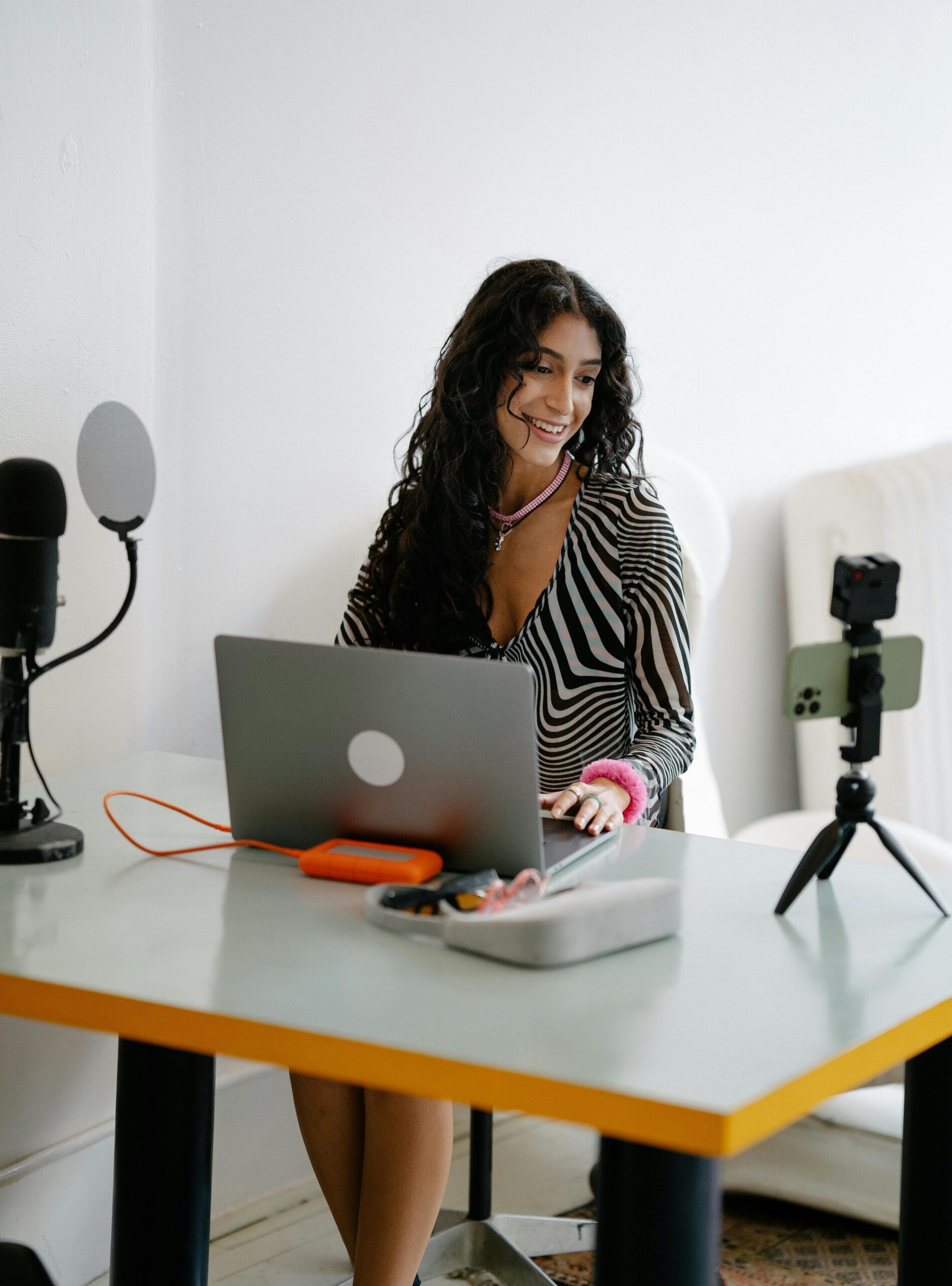 Female content creator at desk with microphone laptop and ring light