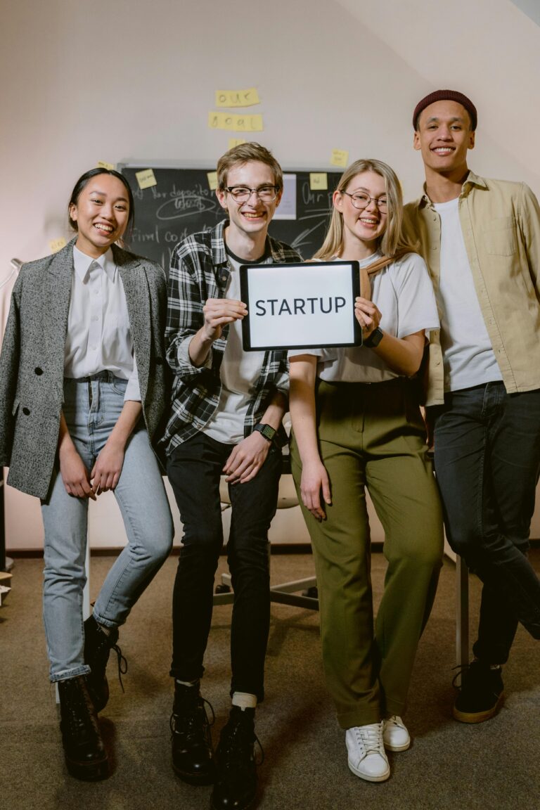 Diverse startup team smiling holding startup sign